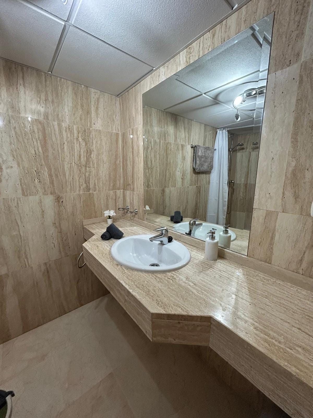 Travertine bathroom with a wide mirror