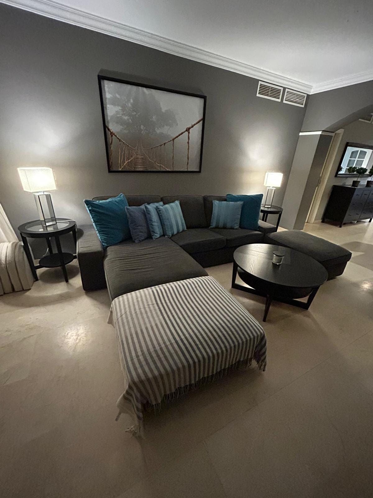Living room in the evening with the corner sofa and a striped pouf