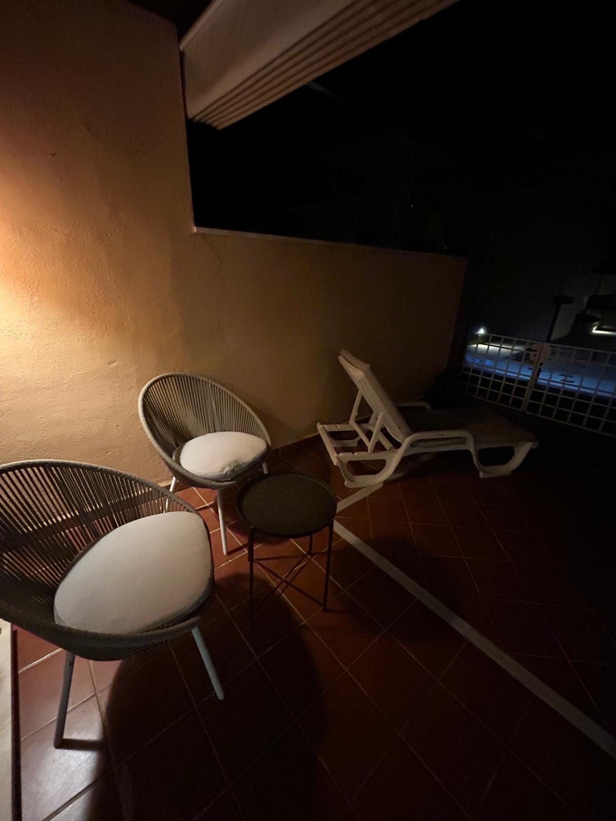 Lounge chairs and a sun lounger on the terrace at night