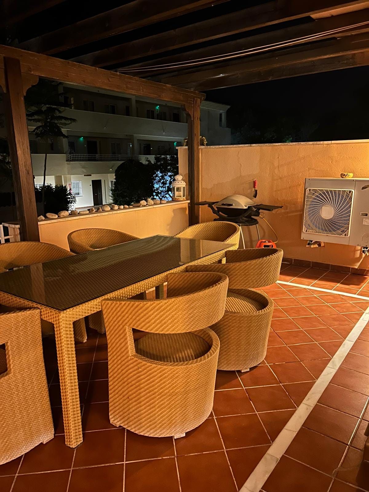Terrace in the evening with the dining table, lanterns and the grill