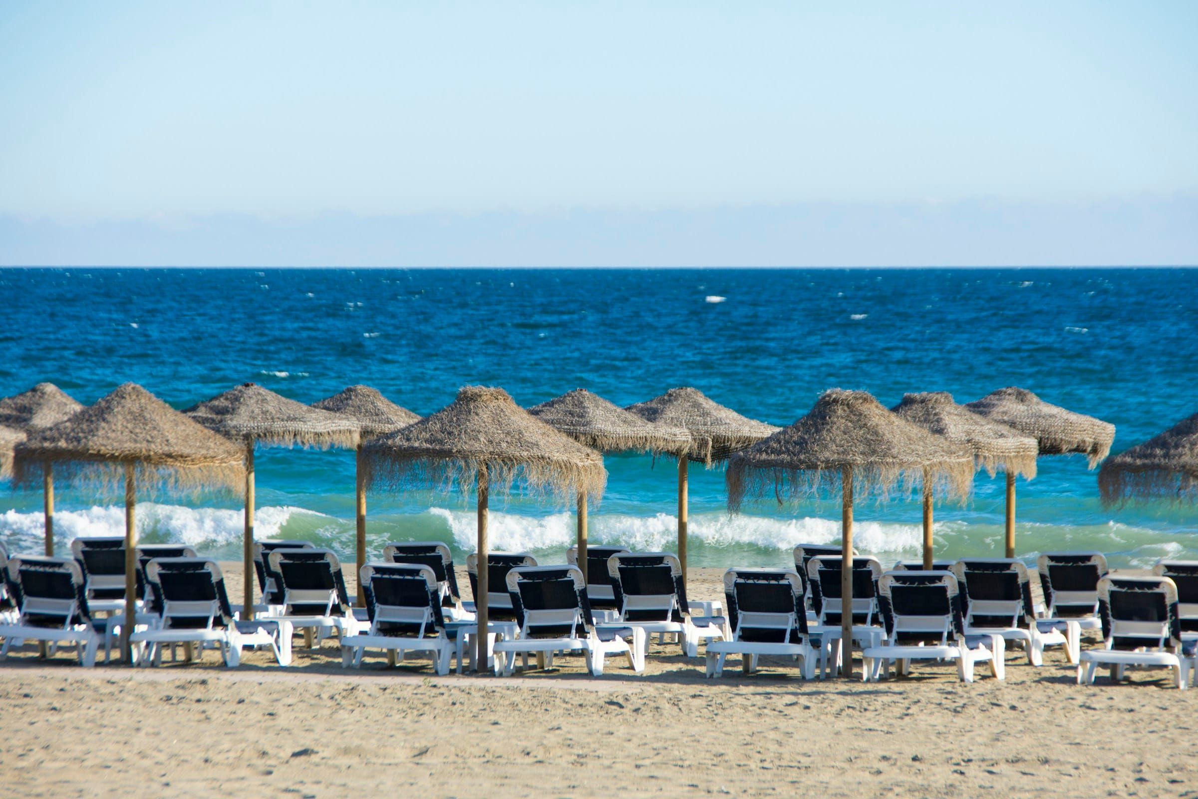 Straw umbrellas and sun loungers on a beach in Marbella
